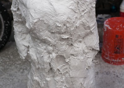 Front view, after plaster. The mold material is 50% plaster of paris, and 50% pure silica. The silica helps keep the mold from disintegrating in the high temperatures needed for melting glass.The cloth pattern (like near the right hand) is from fiberglass cloth. I dip the cloth in the plaster/silica mix, then apply it . It is a lot like making a body cast, but much messier...Tomorrow, we cut the cast in half.